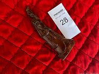 Front view of vintage buffalo horn sculpture resting on red quilted fabric, showing carved details and tapered top.