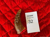 Front side of the carved buffalo horn sculpture showing a figure carved in relief.