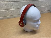 Red Beats by Dr. Dre Solo HD wired headphones on a white mannequin head facing right side profile.