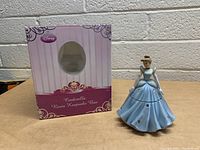 Front and side view of Cinderella resin keepsake box with original packaging box beside it on table.