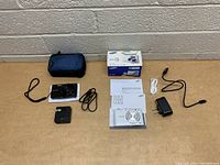 Overview of lot with both cameras, accessories, manuals, chargers, USB cables, and cases shown.