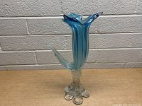 Side angle view of the blue glass vase showing curved design and clear multi-footed base.