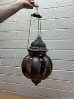 Full view of purple hanging glass candle holder lamp with metal chain, showing globe shape and metal accents