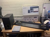 Soundbar and subwoofer unboxed on tabletop with original packaging behind