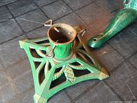 Photo of the green cast metal Christmas tree stand base with decorative leaf cutouts and tree securing screws