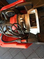 Photo shows Craftsman router in red and black with metal base plate and attached black power cord inside red carrying case.