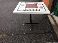 Full view of the table showing metal base and top surface with game board pattern.