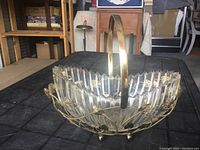 Front angled view of the glass and brass basket showing the glass's scalloped edge and brass floral decoration.