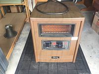 Front view of Classic infrared heater showing wood-finish body, heating element window, and digital control panel with buttons and LED display.