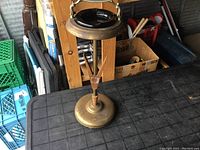 Full view of the ashtray stand showing ceramic ashtray insert, wooden vertical support, and brass base.