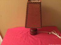 Photo of the entire teak table lamp with original rectangular shade and power cord on pink surface.