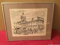 Framed ink drawing of historic building and market scene by Trudy Doyle displayed on wall.