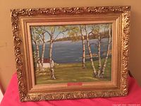 Full view of the framed oil painting showing the lake scene with birch trees and the ornate gilded frame.