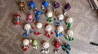 20 colorful Christmas snowball ornaments displayed on carpet. Assorted colors including festive faces and limbs.