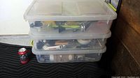 Stacked view of three translucent plastic storage totes with lids, filled with various items inside, showing the size and condition of the totes.