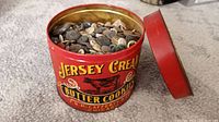 Open red metal tin showing assorted old-fashioned buttons inside.
