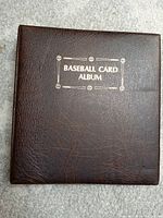 Closed brown baseball card album with 'Baseball Card Album' stamped in gold lettering on front cover.