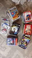 Top down view of several stacks of children's DVDs showing titles like Mighty Machines, Pocoyo, Coraline, Bolt, Inside Out.