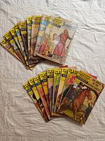 Two stacks of 18 Classics Illustrated comic books arranged on a white cloth background. Covers show various classic literature titles and colorful vintage comic art.