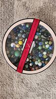 Top view of closed container filled with assorted marbles showing varied colors and sizes.