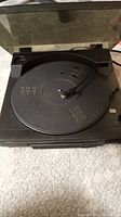 Front view of the Denon DP-25F turntable with dust cover open showing the platter and tonearm.