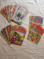 22 early Archie comic books arranged in two overlapping groups on a white surface, showing colorful covers with characters and titles.