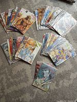 Top view of all comics in multiple stacks on carpeted floor, showing the various colorful covers with martial arts and fantasy artwork.