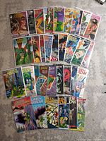 Photo showing 34 Green Arrow comic books arranged in rows on the floor, colorful covers with various issues visible, mostly in good condition.