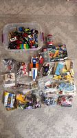 Photo of all items spread on the floor including plastic bins and bags of LEGO pieces, partially assembled models, and boxed set.