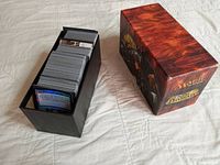 Open black card box filled with assorted Magic: The Gathering cards showing card backs and some faces