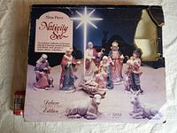 Original box of nine-piece nativity set with a depiction of all figurines, showing some wear and a broken plastic window.