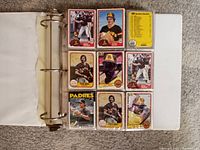 View of 9 baseball cards arranged in a 3x3 grid inside a white 3-inch binder. Cards largely feature San Diego Padres players in vintage design with colored borders and player photos.