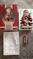 Porcelain Santa Claus figurine displayed next to its original box and styrofoam packaging, size comparison with a soda can.