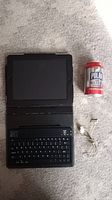 Open iPad in black folio case with keyboard attached, white 30-pin charging cable, and a can of Polar seltzer for scale.