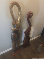 Two tall ceramic elephant sculptures with curved trunks and decorative patterns placed against a wall.