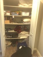 Closet full of bedding: pillows, blankets, books, air mattress storage bag
