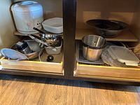Two open kitchen drawers with various cookware including rice cooker, pans, bowls, and food containers