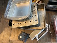 Metal bread loaf pans, square baking pans, perforated trays and box grater stacked inside each other.