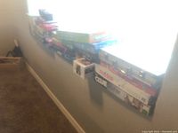 Full length view of many boxed board games stacked on a windowsill showing a variety of titles and a metallic case.