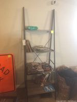 Front side view of tall bookshelf with metal frame and five wooden shelves, showing miscellaneous small items on shelves.