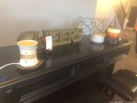 Wide view of all items displayed on black surface: CHEERS sign, wine rack, two candles, ceramic vase, and ceramic wax warmer