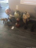 Wide shot of all items showing ceramic globes, vases, wooden elephants, and wooden sculptures