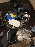Basket with various electronics including white gaming controller, headphones, cables, and Nintendo DS case