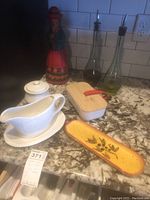 Full view of the lot on kitchen counter showing all items: Gibson gravy boat and covered container, olive oil bottles, butter dish, and figurine