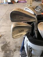 Close-up of multiple Lynx golf irons with Master Model label and club numbers visible.