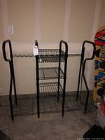 Full view of black metal golf bag storage rack showing two side compartments for golf bags and three center wire shelves.