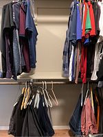 Clothing items hanging in closet including over 30 men's shirts and over 10 pants along with hangers and hats visible.