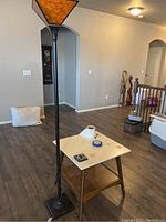 Floor lamp and square table positioned in living room area with wood flooring and neutral wall colors.