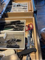 Drawer showing Victorinox knives, scissors, and kitchen utensils such as whisks and peelers.