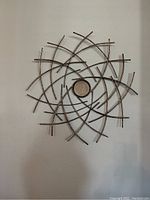 Metal wall art mounted on a white wall, showing full front view of design and structure.
